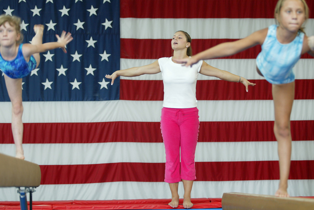 Former USA Olympic Gymnast Dominique Moceanu, 22, instructs two gymnasts, Kara Crabtree, 7, of Groveport, left, and Brooke Schottenstein, 9, right, also of Groveport, Monday August 2, 2004 at Capitol City Gym in Groveport,OH.  Moceanu, who is now living in Cleveland, and going to school, is teaching a two day camp for Capitol City Gym.